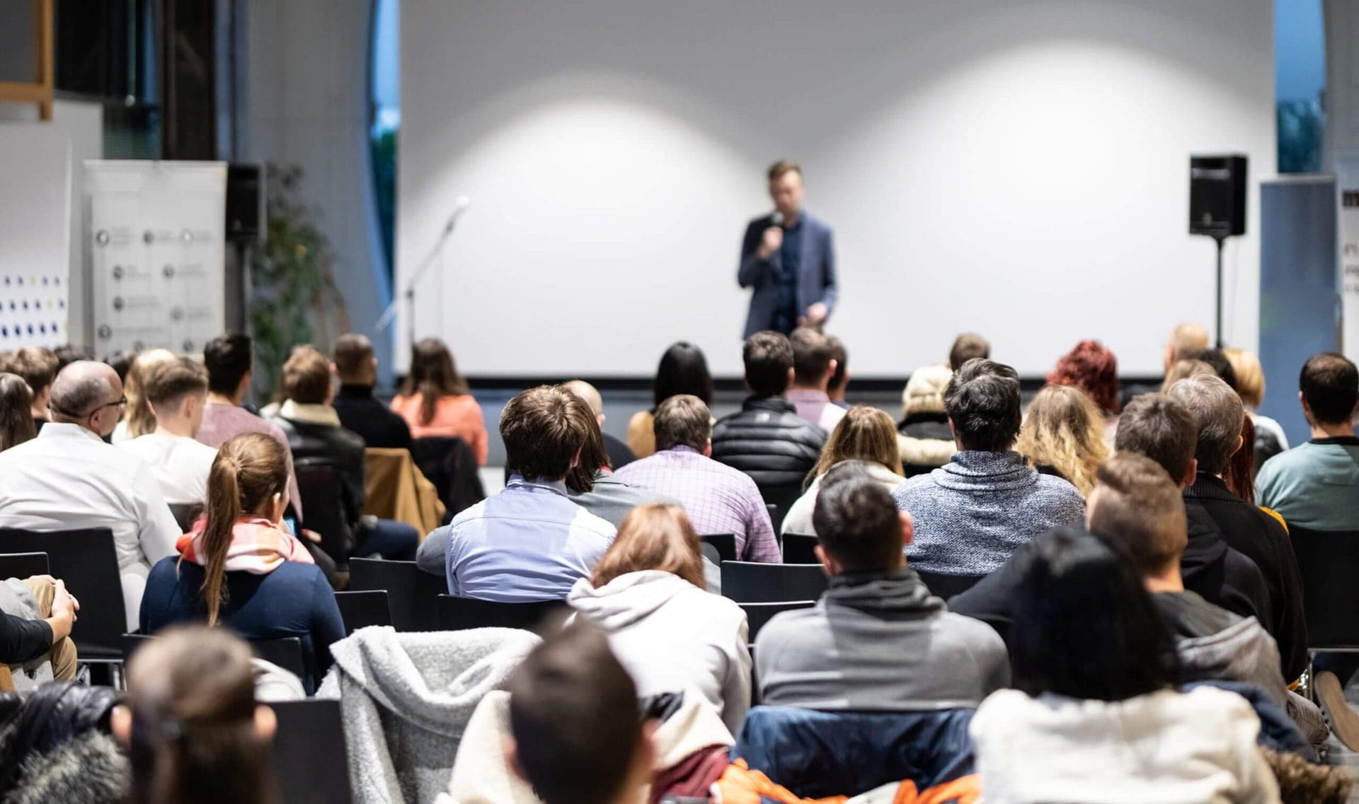 Saal mit Publikum und Rednerin während einer Tagung